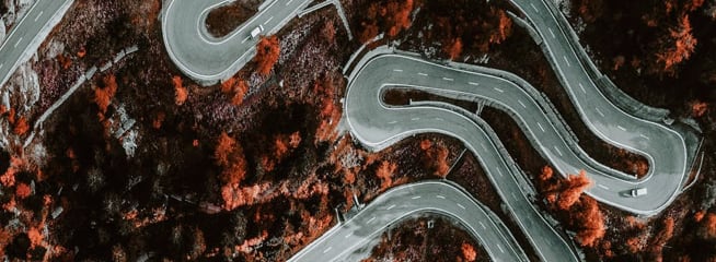 An image from above of zigzag road on rugged mountainside