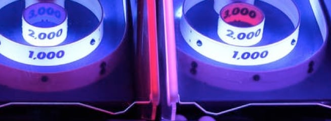 An close up image of an arcade machine under dark blue & pink neon light